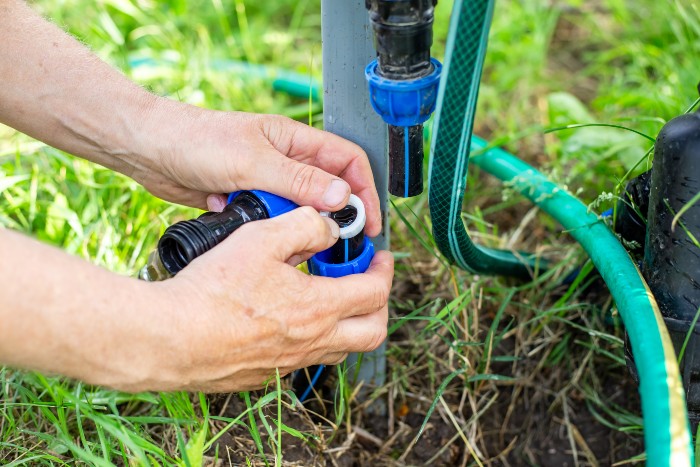 Installing an additional faucet to drain water from a drip irrigation system. The gardener attaches the sealing collar of the connecting fitting to the section of HDPE pipe where the faucet is inserted.